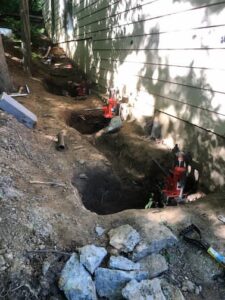 employees dig holes next to foundation for piers