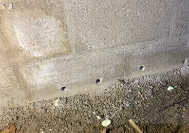 small drainage holes drilled into basement wall
